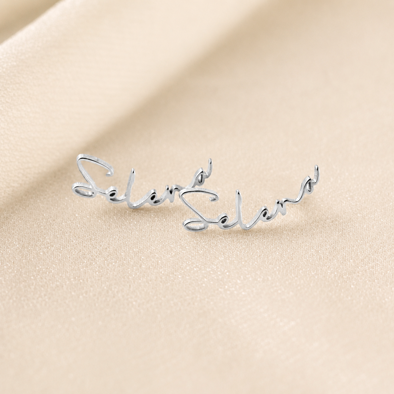 Silver bracelet with 'Selena' engraving on a beige background